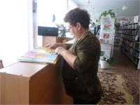 Социальный работник Светлана Борисовна Шельпякова знакомится с печатными материалами в Подовиновской сельской библиотеке